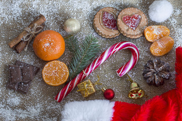 a snowy Christmas holiday composition with a cane and ripe mandarins and a New Year hat