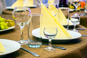 The table in the restaurant. On the table there are empty wine glasses, napkins and a plates