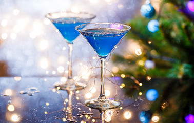 Christmas image of two wine glasses with blue cocktail and garland