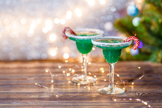 Christmas image of two wine glasses with green cocktail, caramel sticks