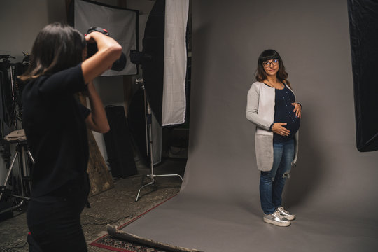 Pregnant woman doing a photoshoot with a female photographer in a studio