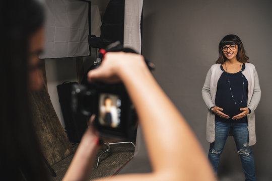 Pregnant woman doing a photoshoot with a female photographer in a studio