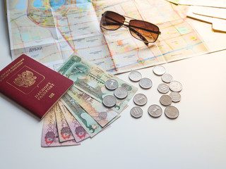 Fototapeta premium Arab dirhams and a Russian passport on the background of the card and sunglasses. The concept of travel. 