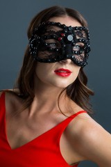 Obraz premium Woman wearing masquerade mask against black background