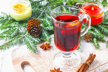 New Year's mulled wine in a glass on the background of twigs, candles and garlands.
