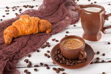 Freshly baked croissants on brown napkin, cream, to cups of coffee in ceramic dishes on white wooden background. Fresh pastries for breakfast. Delicious dessert. Closeup photography.Horizontal banner
