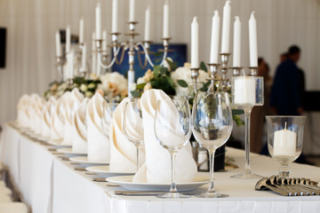 Glasses and candles on the table, serving, people in the background