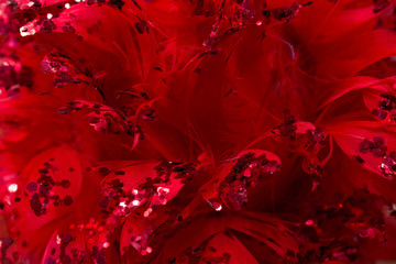 Christmas and New Year decorations: background of red feathers and sparkles, soft focus.
