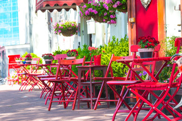 Fototapeta na wymiar Red tables and chairs at a sidewalk cafe at european city