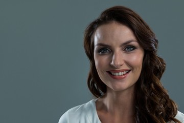 Fototapeta premium Smiling woman looking at camera against grey background