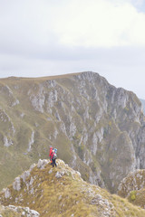 Hikers with backpacks relaxing on top of a mountain and enjoying the view of valley