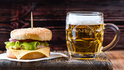 hamburger on a wooden board with a mug of beer