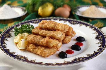 Perch fillet fried in breadcrumbs.On the plate with slices of lemon and herbs.