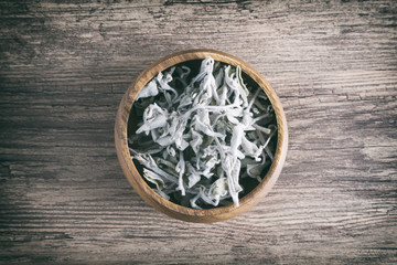 Wooden Bowl Full Of Dried Green Sage Leaves On A Wooden Surface