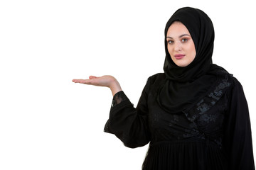 studio shot of young woman wearing traditional arabic clothing. she's holding her hand to the side