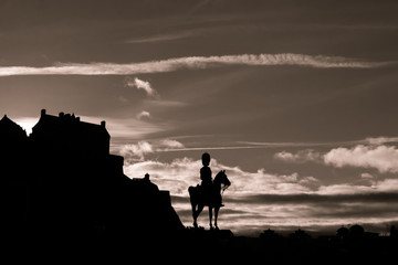 Edinburgh Castle and military statue silhoeutted against a cloudy dusk sky