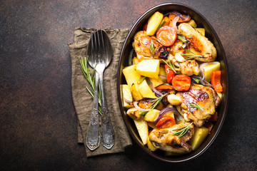 Chicken baked with vegetables. Top view with copy space on dark rusty table.