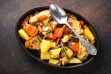 Chicken baked with vegetables. Top view on dark table.