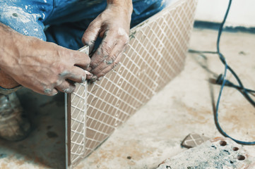 Laying ceramic floor tiles - man hands marking tile to be cut, closeup