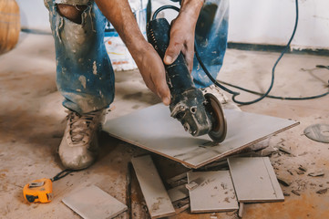 worker cutting a tile using an angle grinder at construction site