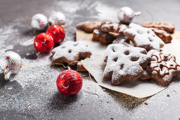 Fototapeta na wymiar Christmas cookies with powdered sugar and candies on a wooden, cutting board on a gray background