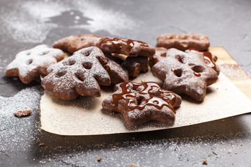 Christmas cookies with powdered sugar on a wooden, cutting board on a gray background