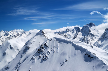 Fototapeta na wymiar Winter mountains with snow cornice and blue sky with clouds