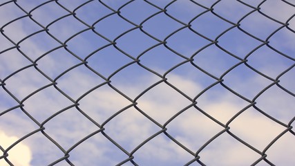 Naklejka premium Steel net with blue sky and white clouds