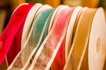 Close up of rolls of colorful cloth tape, over a wooden table in a blurred background