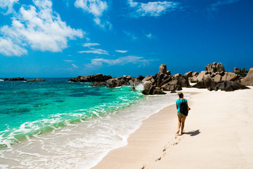 Woman walking on white sand, the pathway for an amazing natural beach, tropical landscape Anse...