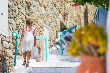 Obraz na płótnie Canvas Adorable girl outdoors in greek village. Kid at street of typical greek traditional village with white stairs on greek island