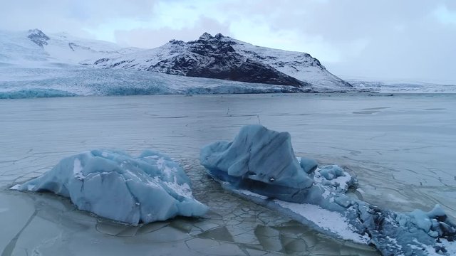 Aerial footage of blue iceberg in frozen gracier lagoon, Fjallsárlón Iceland