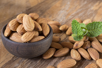 Almonds in a black bowl against dark rustic wooden background