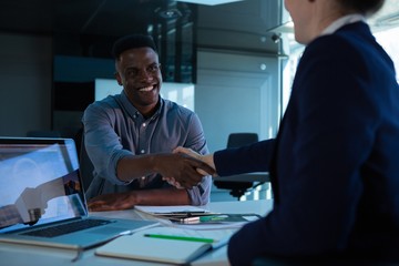 Executives shaking hands at desk