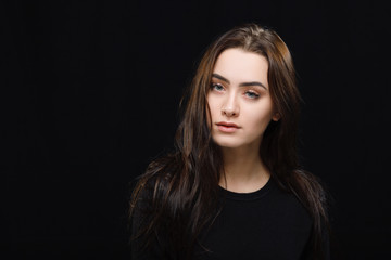 Naklejka premium Low key portrait of young adorable caucasian woman in black sweater on dark background. Facial expressions and emotion concept.