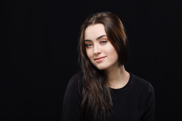 Low key portrait of young adorable caucasian woman in black sweater on dark background. Facial expressions and emotion concept.