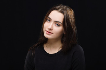 Low key portrait of young adorable caucasian woman in black sweater on dark background. Facial expressions and emotion concept.