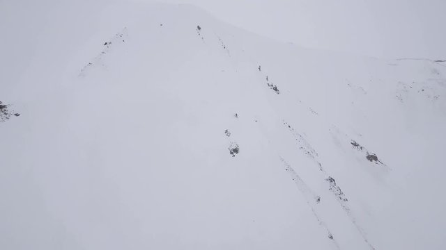 Person snowboards down steep mountain, Iceland aerial