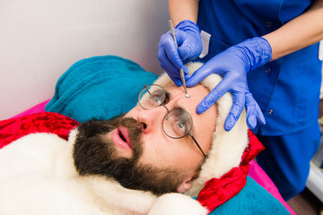 Santa Claus receiving facial beauty treatment.