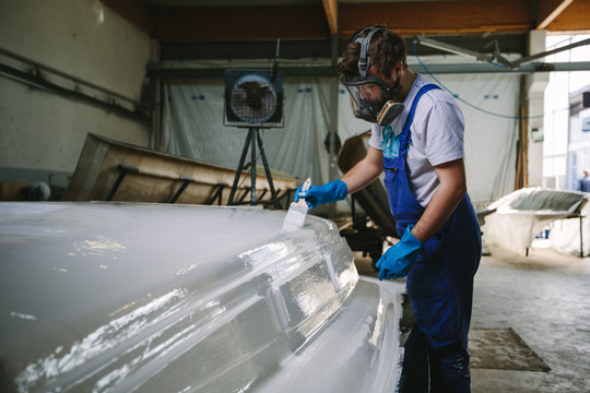 Man in mask brushing ship construction in white color