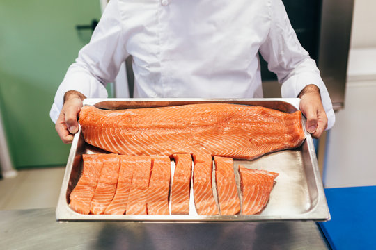Chef showing to camera a tray full of fresh salmon