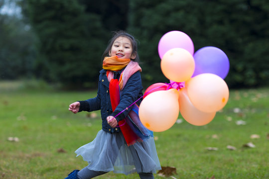 One little Girl playing with colorful balloon outdoor in the aut