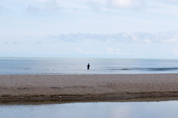 Fototapeta na wymiar background of beach with tiny fisherman in the sea