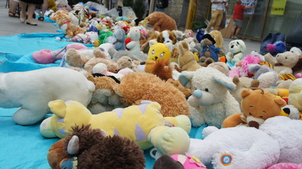 Christmas gift for kids in streets, so many toys, recycling baby toys and teddies made of cheap plastic or fabric in bulk display at garage sale of flea market for over-consumption society, outdoors