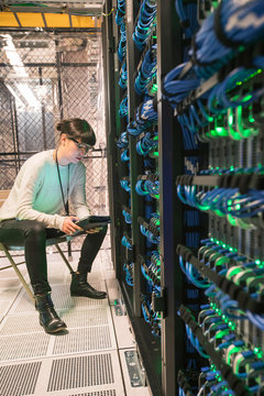 Server room tech glows green from the light on the back of a ser