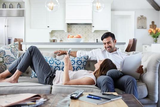 Young Couple relaxing on sofa looking at mobile phone after work