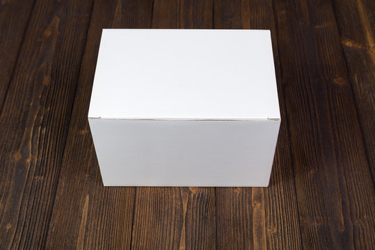 Empty white gift box or tray for mock up on dark wooden table with copy space.