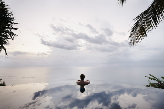 Young  man relaxing in an infinity pool in Bali