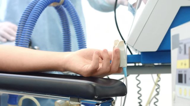 Patient's arm with finger pulse meter in surgery room