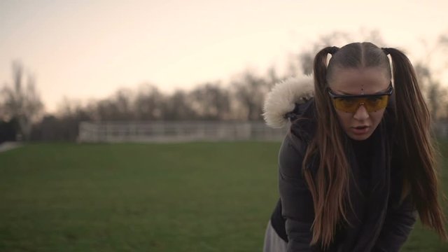 Attractive young hipster woman in a stylish look dancing freestyle on urban background at sunset or dusk